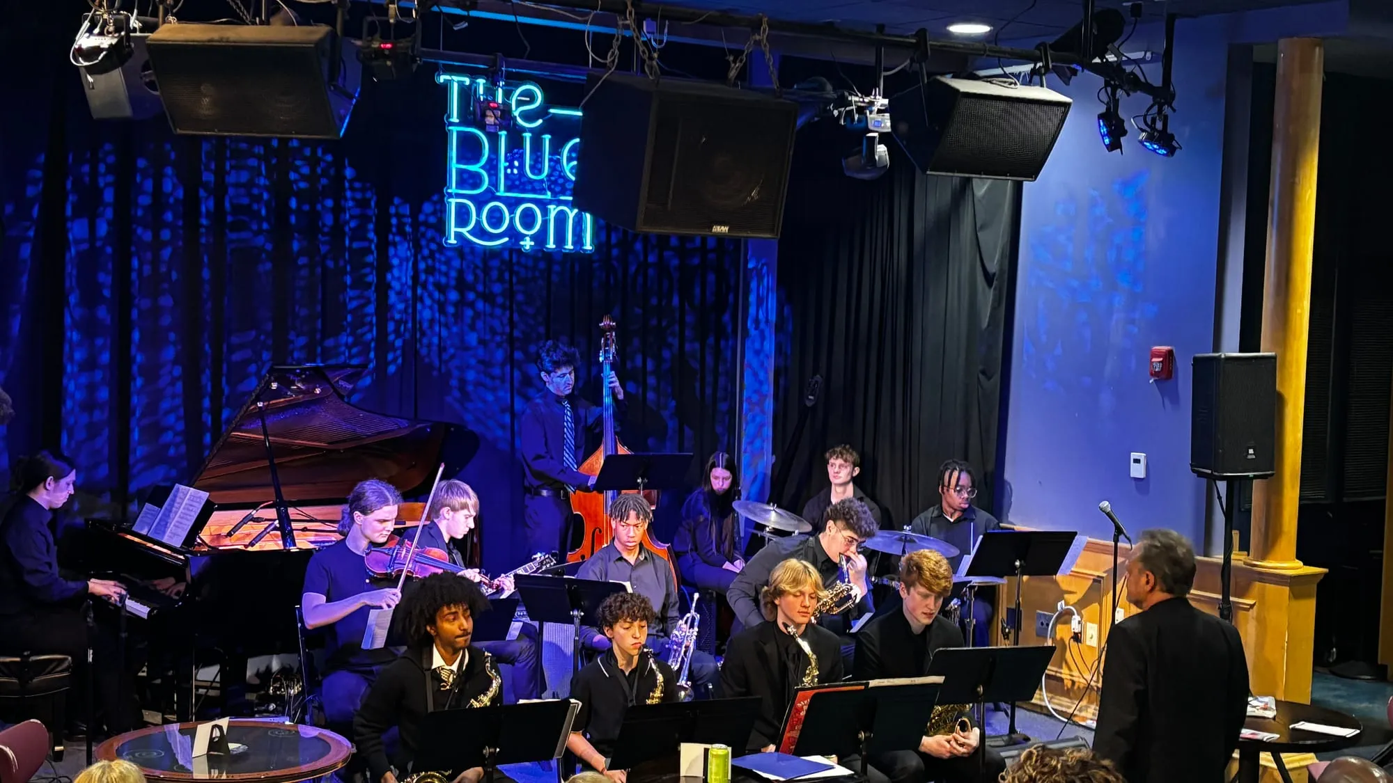 The 18th Street Combo performs on stage under blue stage lighting, with piano and horns.