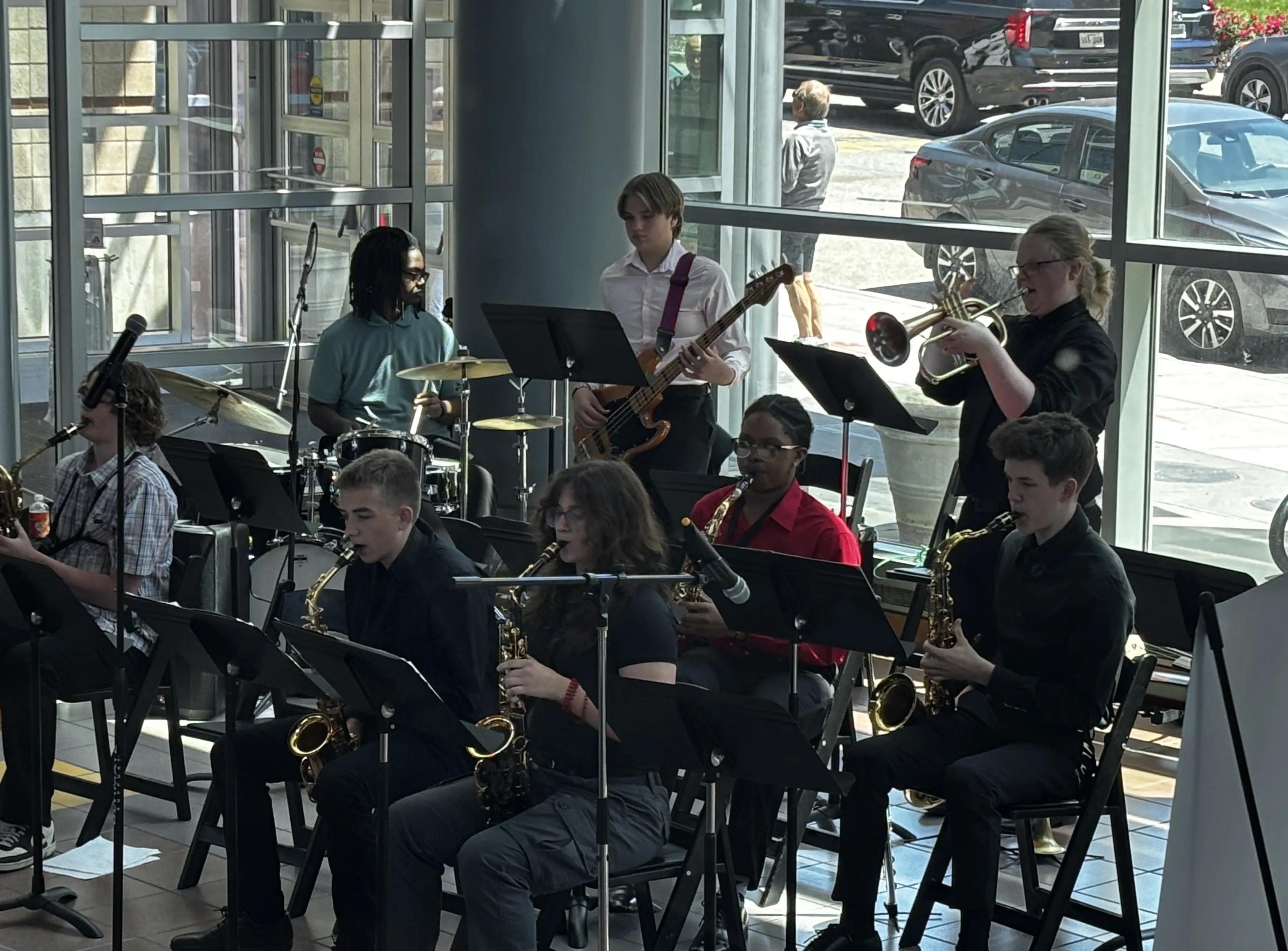 The Vine Street Combo performs, a seated row of student saxophonists reading from music stands by tall windows.